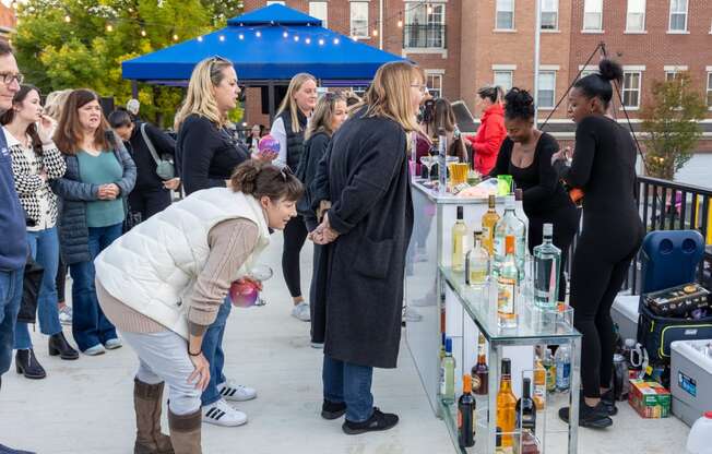 a group of people standing around a table with bottles of alcohol