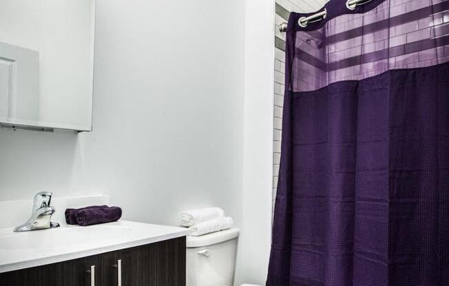 bathroom with white tile shower, modern wooden cabinet, and white walls