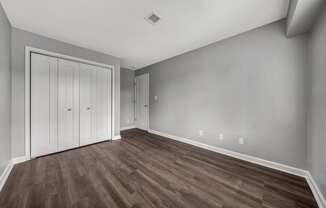 an empty living room with wood flooring and a door to a closet