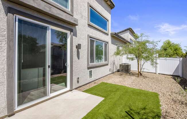 a backyard with a grassy area and a patio with a tree