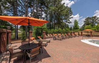 a patio with chairs and umbrellas and a pool