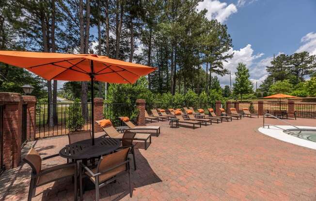 a patio with chairs and umbrellas and a pool