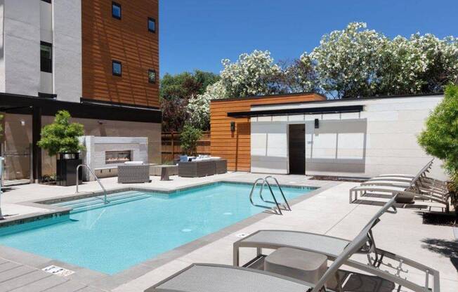 the pool is next to a pool house with chairs