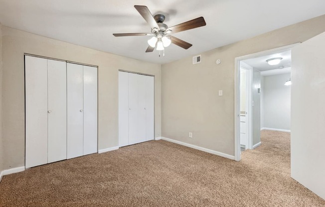 an empty living room with carpet and a ceiling fan