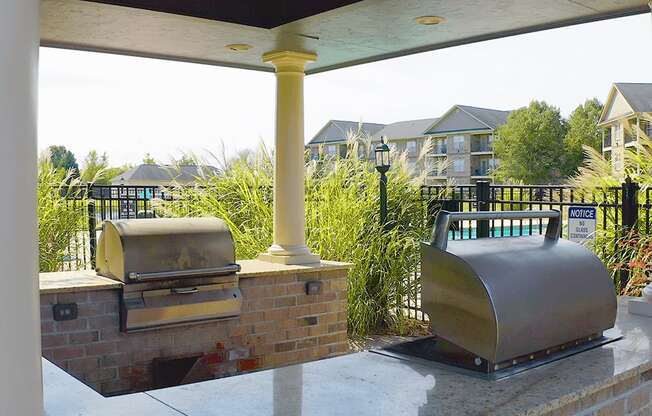 A BBQ grill is on a patio with a notice sign on the fence.