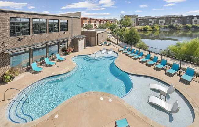 A large outdoor swimming pool with lounge chairs and a slide.