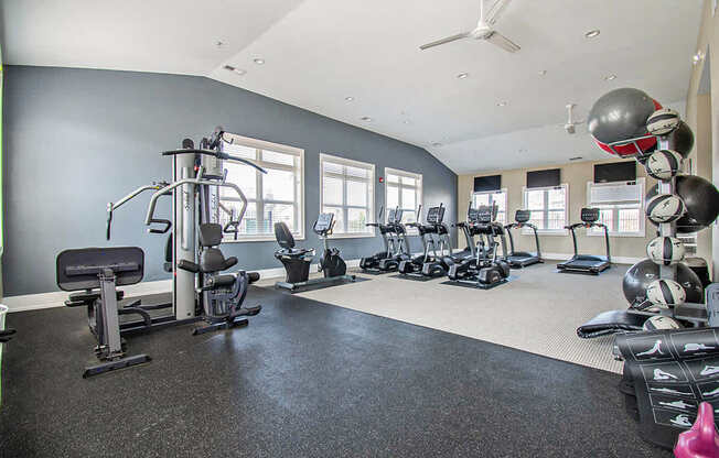 A spacious fitness center with a variety of equipment including treadmills, weights, and exercise machines at Strathmore Apartment Homes, West Des Moines, IA