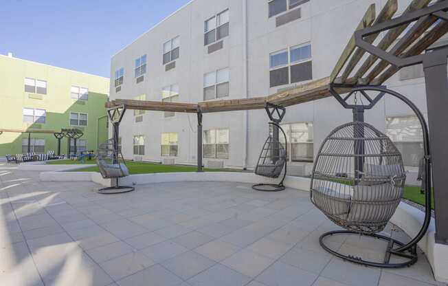 a courtyard with swing chairs in front of a building