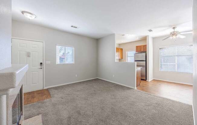 A spacious living room with a grey carpet and a ceiling fan.