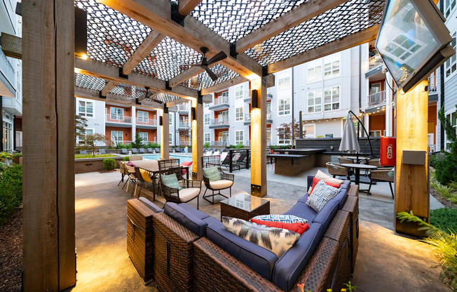 an outdoor patio with wicker furniture and a pergola  at Abberly Noda Vista Apartment Homes, Charlotte