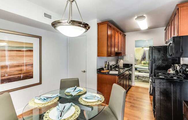 A modern kitchen with a glass dining table set for four.