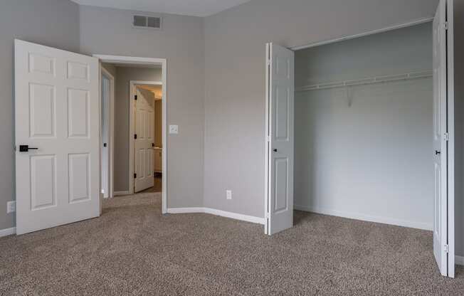 an empty bedroom with two doors and a closet