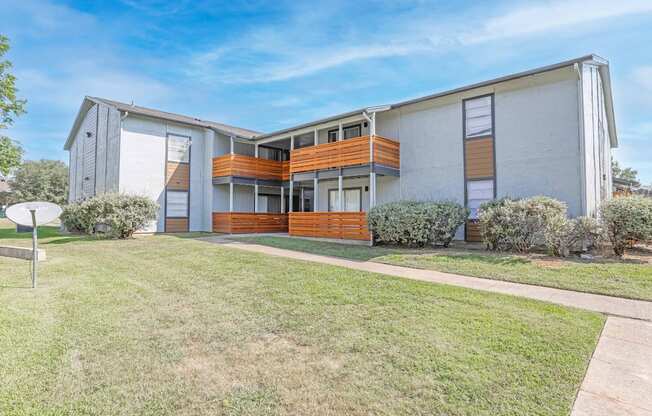 A modern two-story apartment building with a white exterior and a balcony on the second floor and patio on the first floor at The Marq apartments in Shreveport, LA