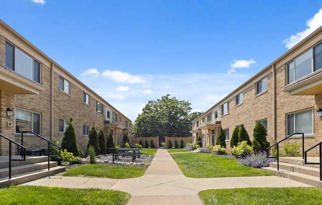 Courtyard view of Monon Court vintage apartment buildings with lush landscaping and walkways in Broad Ripple neighborhood