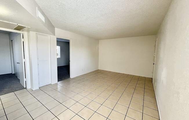 A room with white walls and tile flooring with a door on the left.