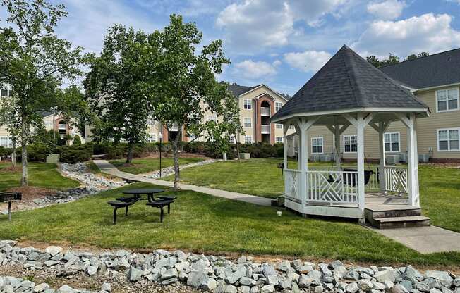 a gazebo sits in the middle of a grassy area with a picnic table