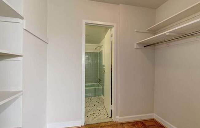 A white hallway with a doorway leading to a bathroom.