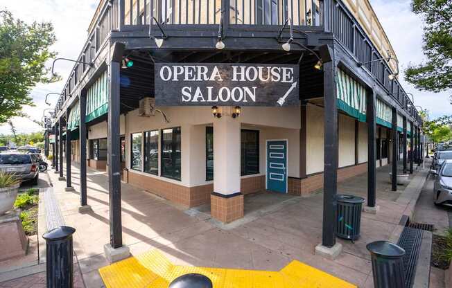 A white building with a black awning that says Opera House Saloon.