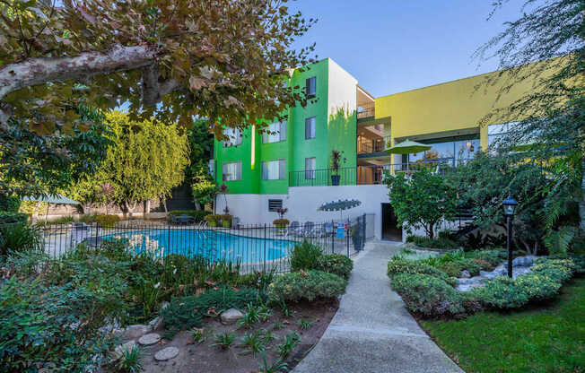 A green and yellow building with a pool in the backyard.