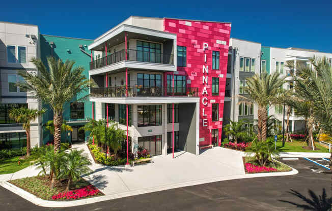 a building with a red and white facade and palm trees at Pinnacle Apartments, Jacksonville, FL, 32256