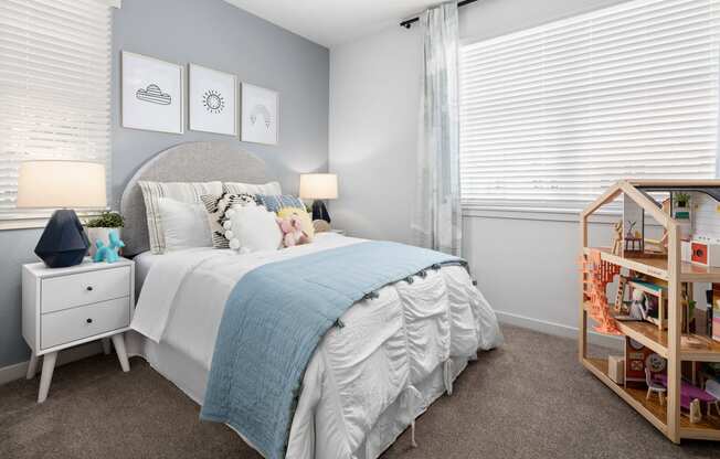 Bedroom with Plush Carpet Flooring, Bed, Nightstands with Lamps, Wall Decor, Accent Wall, and Two Windows with Blinds at Solstice at Fiddyment Ranch, California