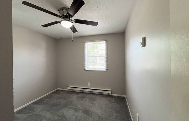 an empty room with a ceiling fan and a window