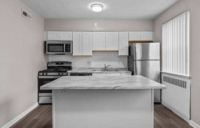 an empty kitchen with white cabinets and stainless steel appliances and a marble counter top
