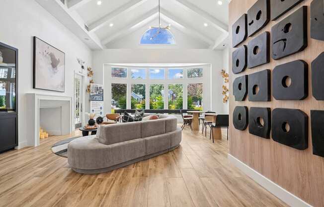 A modern living room with a grey sofa and a wooden wall with black cut outs.