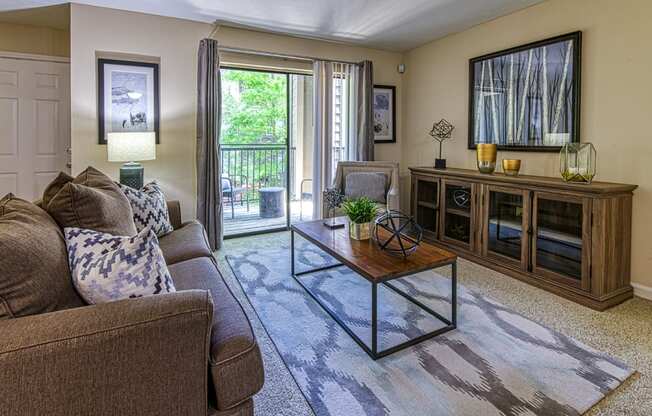 Apartments in Vinings, GA with In-Unit Washer and Dryer - Wynnwood Vinings - Furnished Living Room with Carpet Flooring and a Sliding Glass Door to a Private Balcony