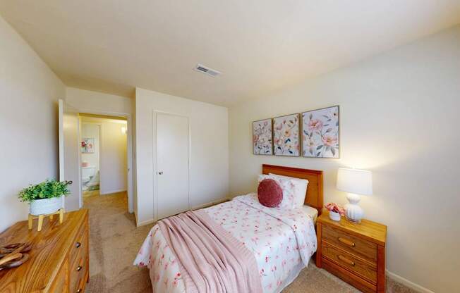 A bedroom with a pink bedspread and a wooden dresser.