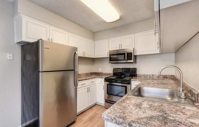 Kitchen with ample counter space, white cabinetry and stainless steel appliance package