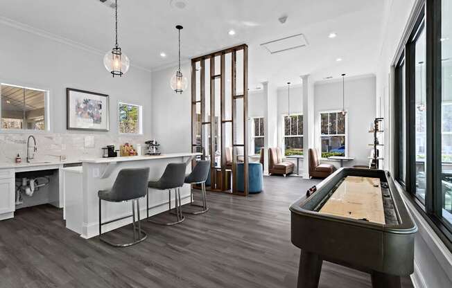 A billiard table is in the middle of a room with a bar and chairs.