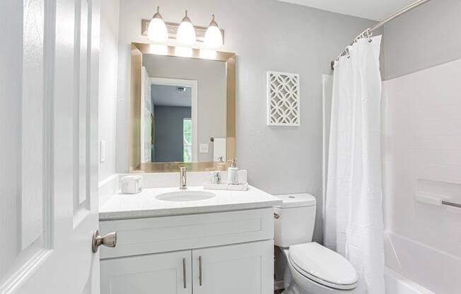 A white bathroom with a sink, toilet, and shower.