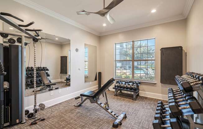 a workout room with weights and cardio equipment and a window