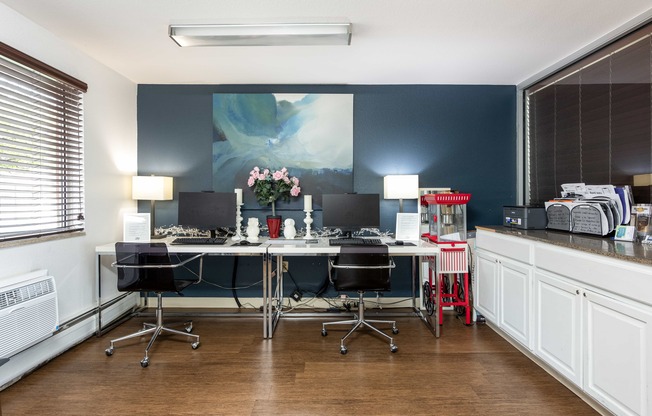 an office with desks and chairs and a painting on the wall