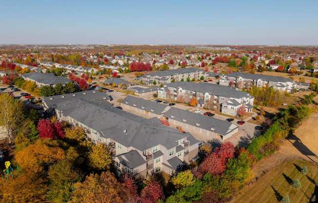 An aerial view of a residential area with apartment buildings and trees in autumn colors.