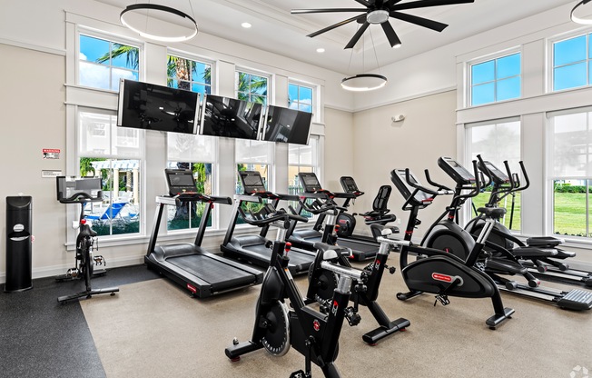 A spacious gym with treadmills, elliptical machines, and a television.