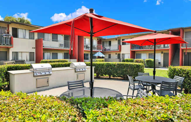 a patio with tables and umbrellas in front of an apartment building