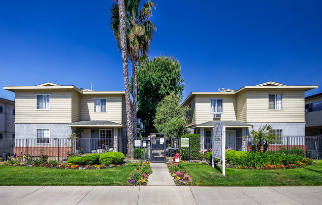 a sidewalk in front of two houses with a palm tree