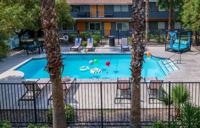 Aerial view of Community pool near Las Vegas strip and Fifteen 50 apartment buildings. Pool is surrounded by patio furniture and palm trees