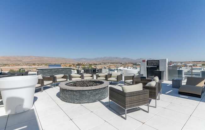 a fire pit and lounge area on the roof of a building with mountains in the background