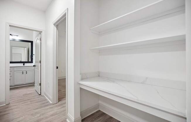 A white hallway with a mirror and a bench.