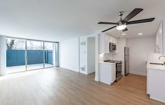 an empty living room and kitchen with a sliding glass door to a patio at Avenue Two Apartments, California