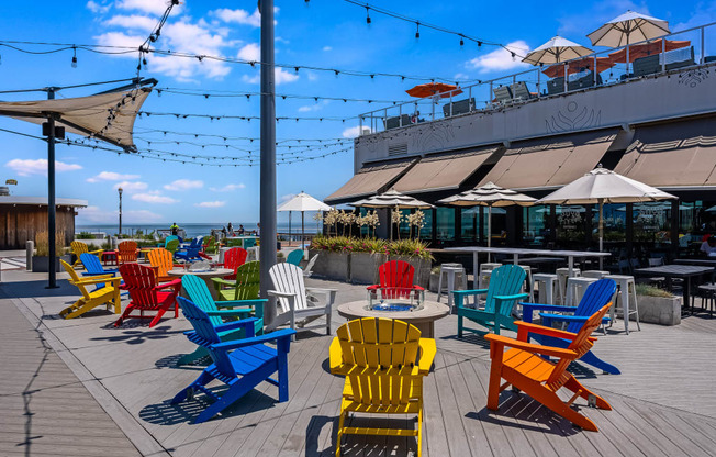 A row of colorful chairs are lined up on a wooden deck.