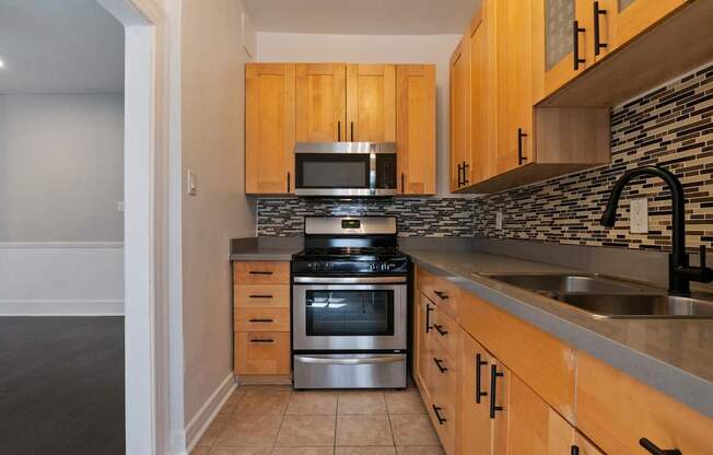 A kitchen with wooden cabinets and a stone backsplash at Brookmore Apartments Pasadena, CA