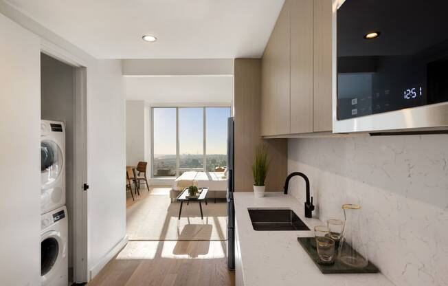 a kitchen with a sink and a dishwasher and a living room with a window at The Paxton, Brooklyn, NY 11201