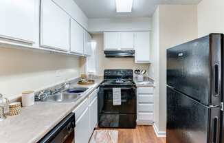 a kitchen with white cabinets and black appliances