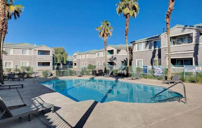 A swimming pool surrounded by palm trees and lounge chairs.