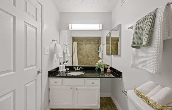 a white bathroom with a black counter top and a mirror