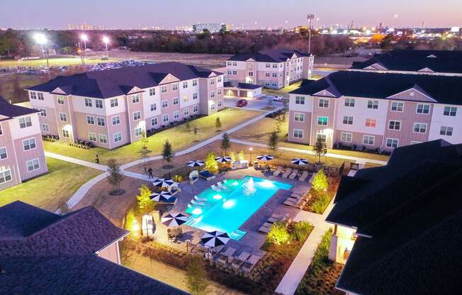 an aerial view of a resort style swimming pool at night at 55 Fifty at Northwest Crossing, Texas